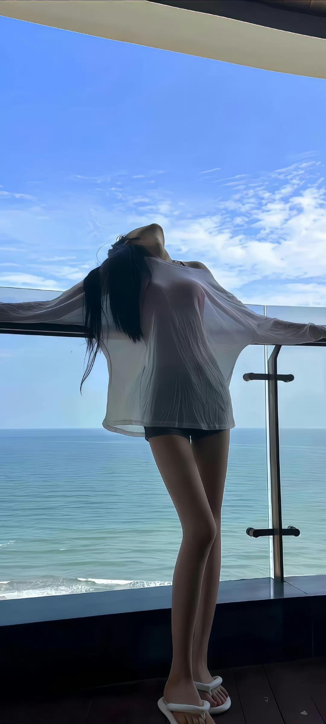 长头发和白衬衫的女人在窗外倾斜。