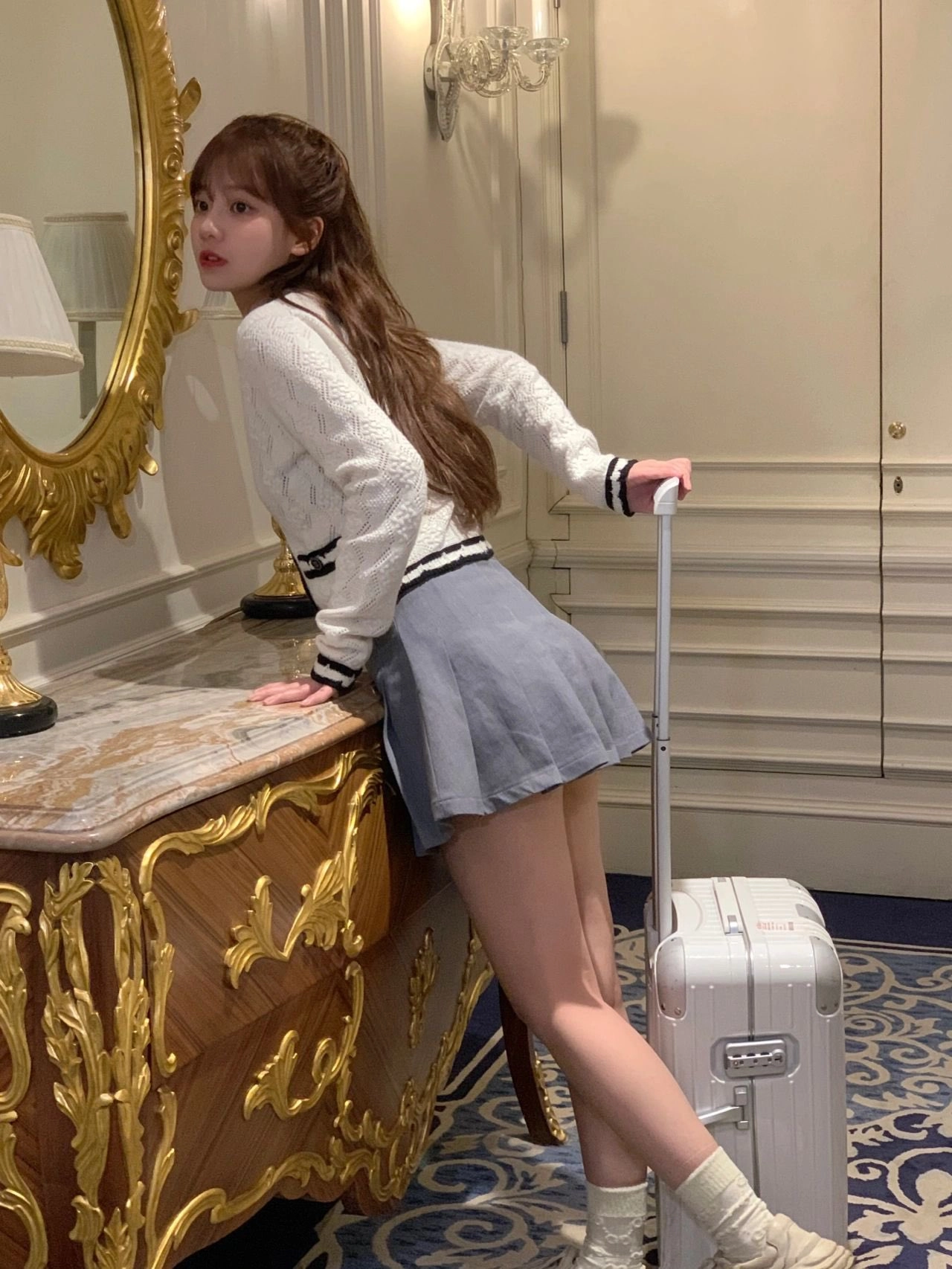 穿着灰色裙子和白色衬衫的女人正在拉一个行李箱。