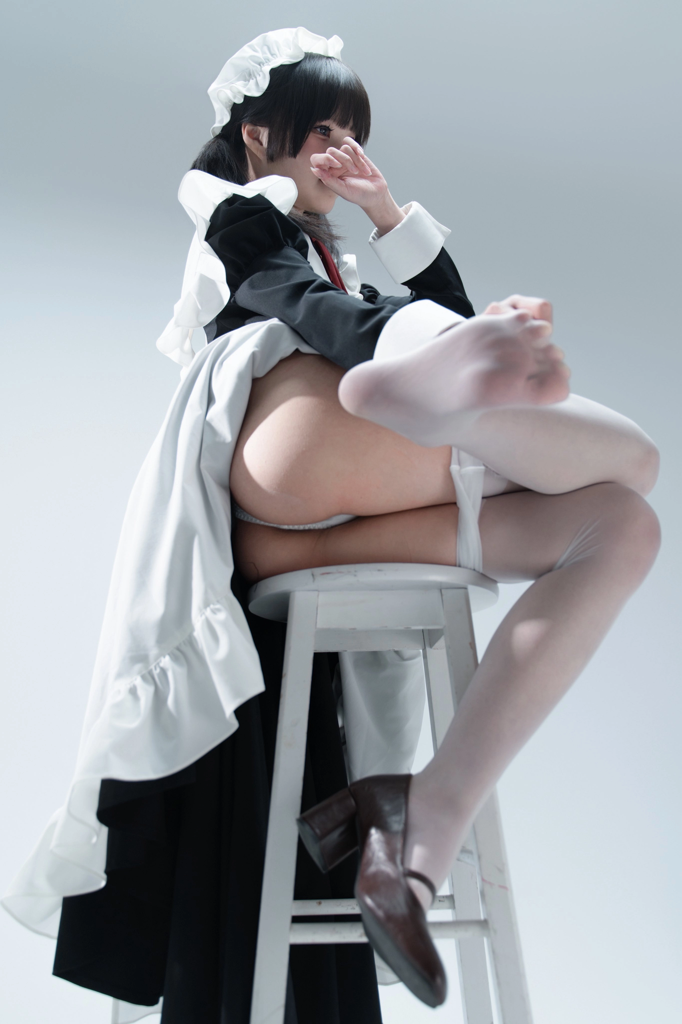 一位穿着黑白裙子的女仆坐在椅子上。