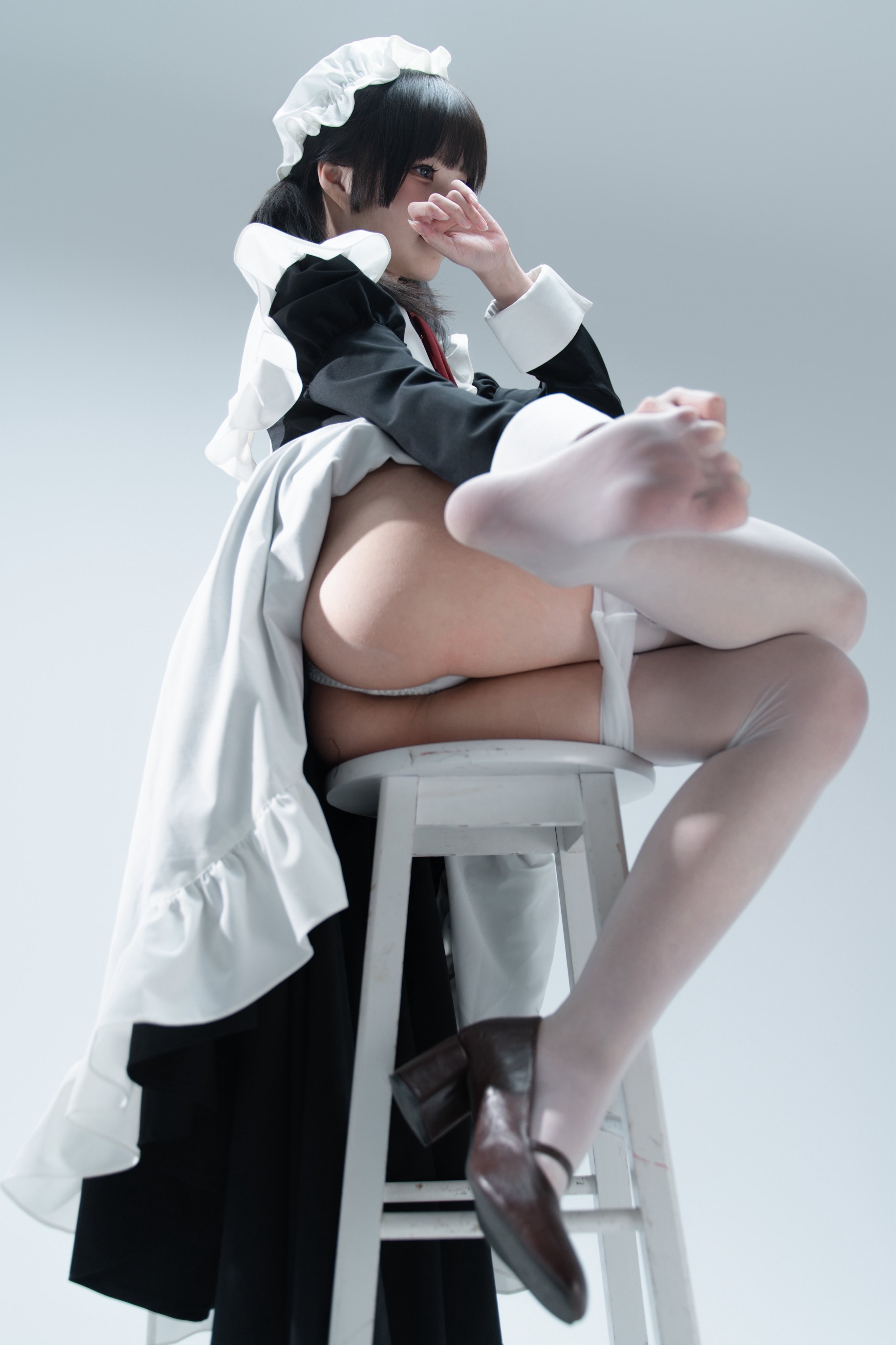 一位穿着黑白裙子的女仆坐在椅子上。