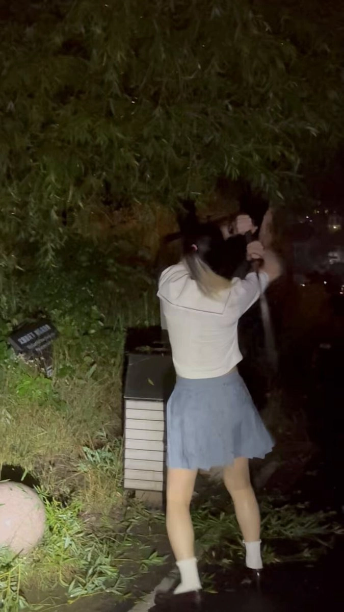 一位穿着白色衬衫和蓝色裙子的女人正在摇摆棒球蝙蝠。