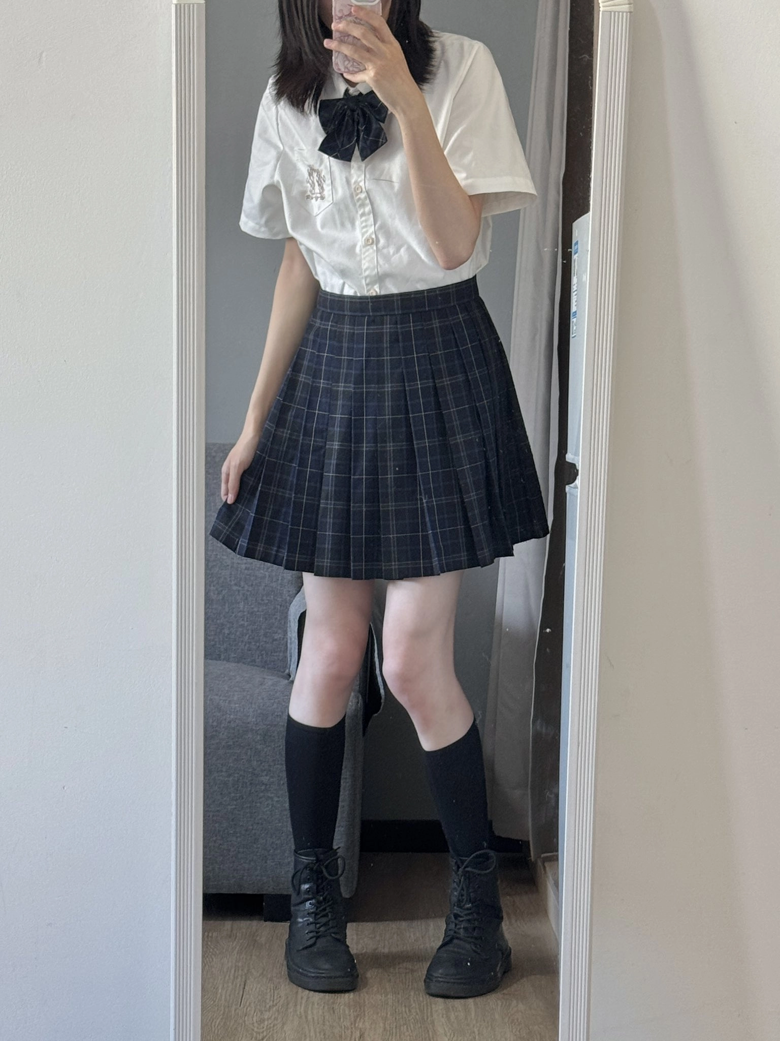 一位穿着一件白色衬衫和一件白色裙子的女人在镜子前拍了一张自拍。