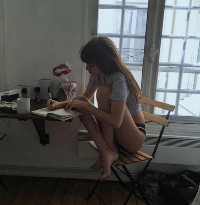 女人坐在椅子上,在一本书里写作。