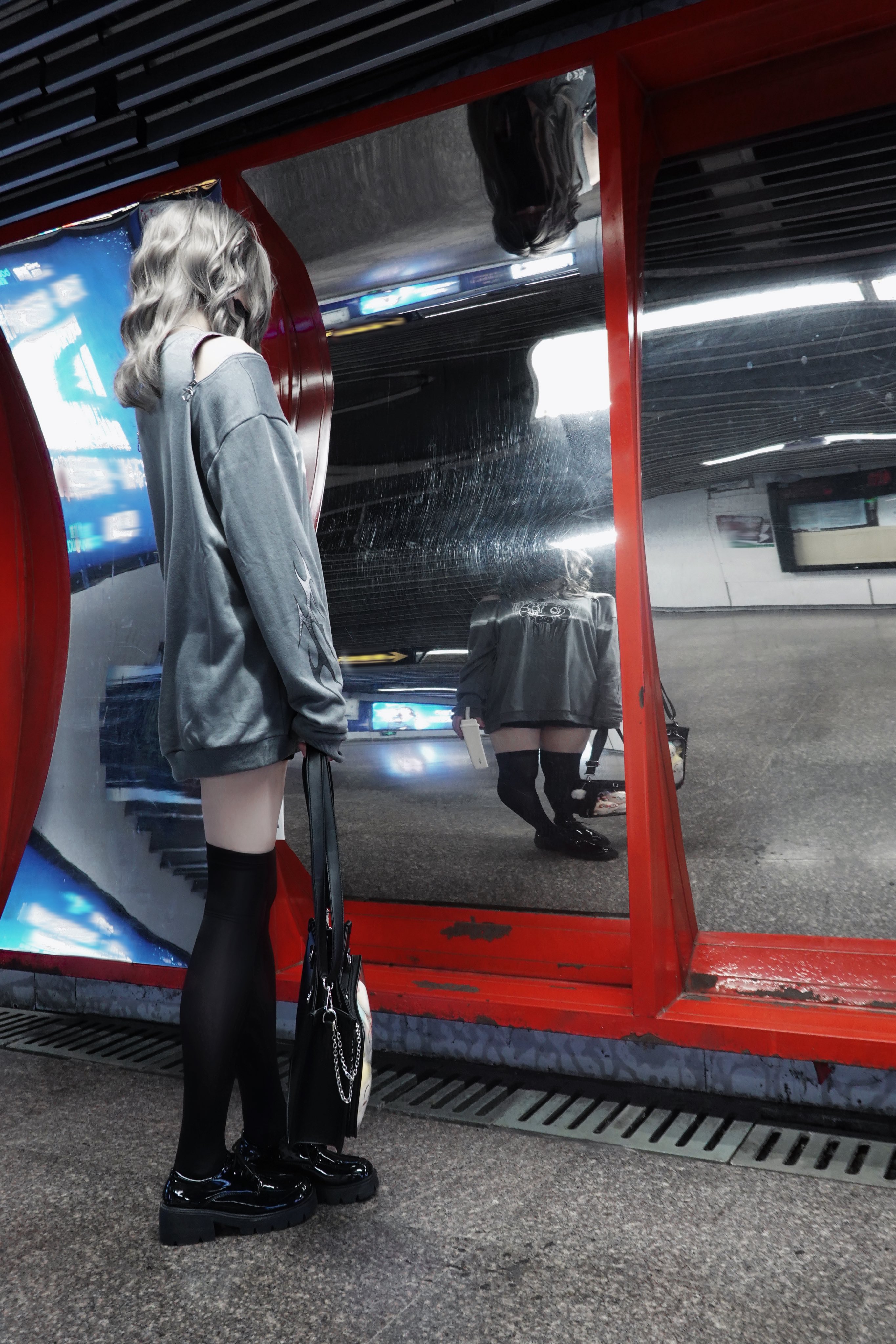 穿着灰色衬衫和黑色衬衫的女人站在镜子前。