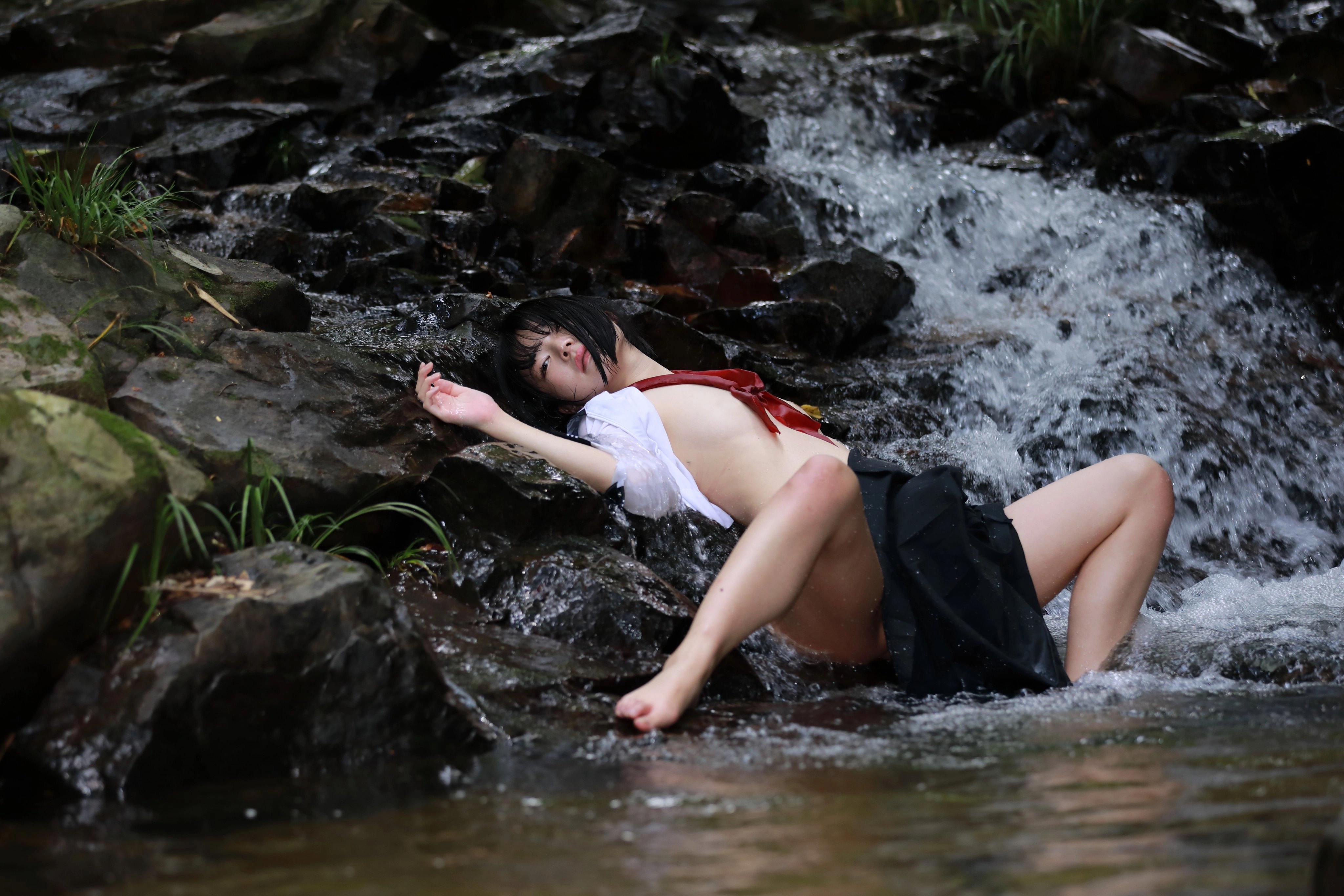 女人躺在河里的一块岩石上。