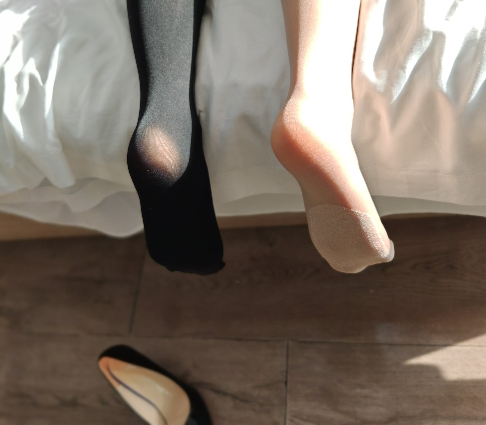 一双黑色袜子和一双粉红色的袜子在床上。