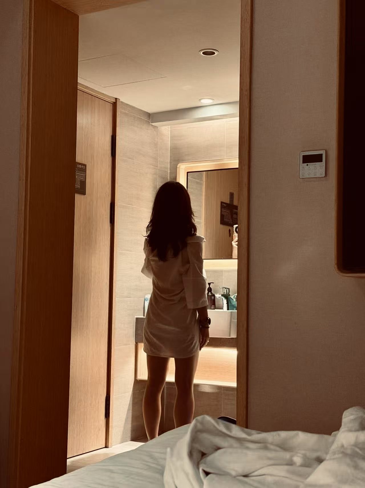 穿白衣的女人站在浴室里。