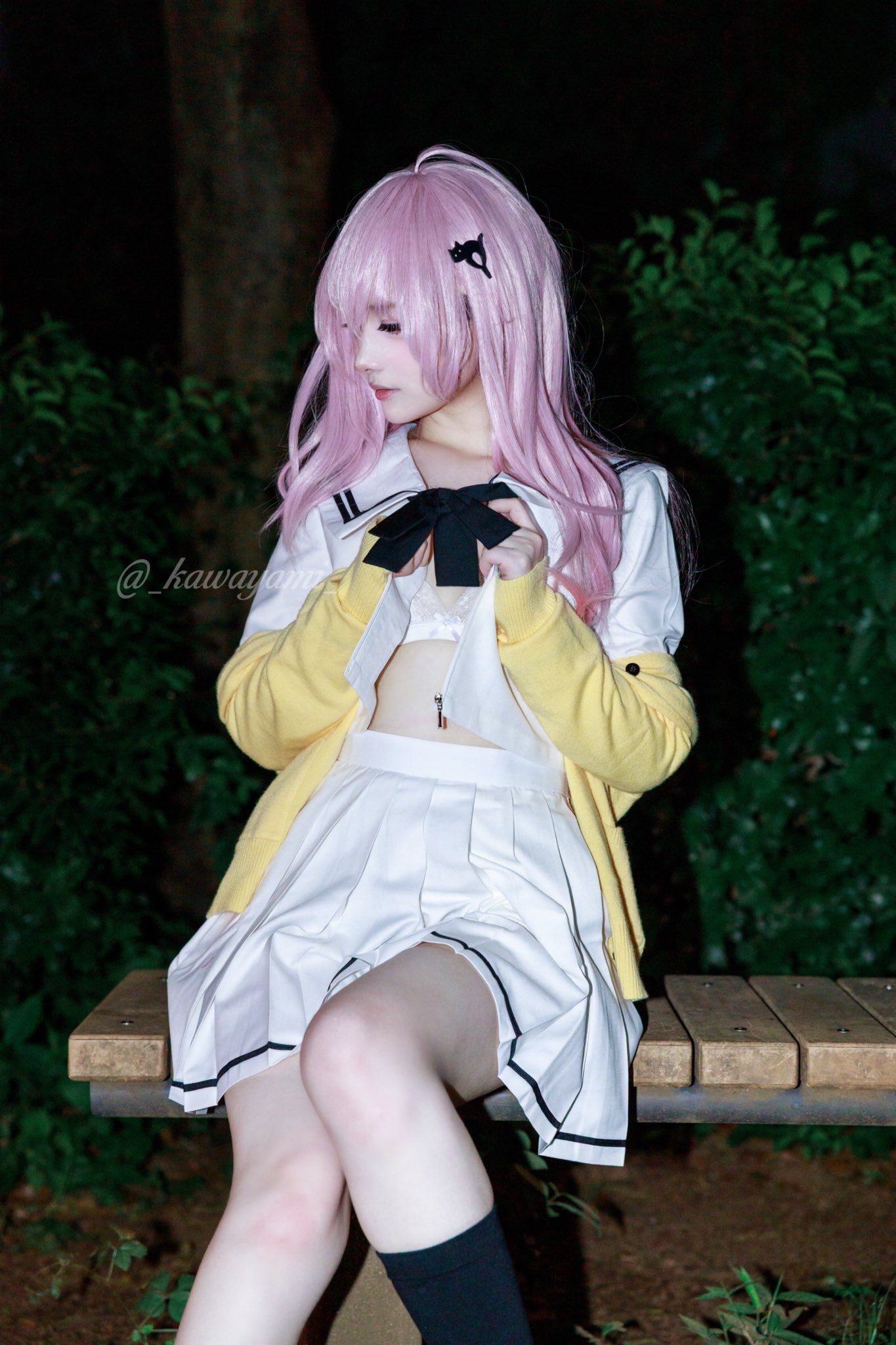 穿着白色裙子和黑色弓的女孩坐在一个凳子上。