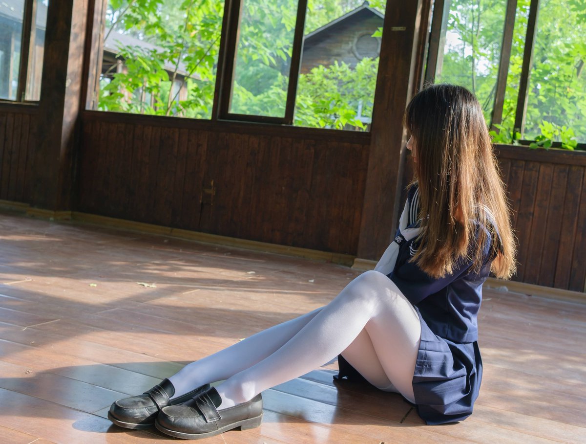 穿着蓝色裙子和白色袜子的女孩坐在一个步骤上。