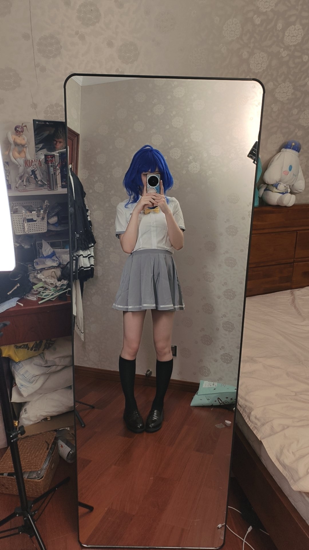 一位穿着蓝色裙子和白色衬衫的女人在镜子前拍自拍。