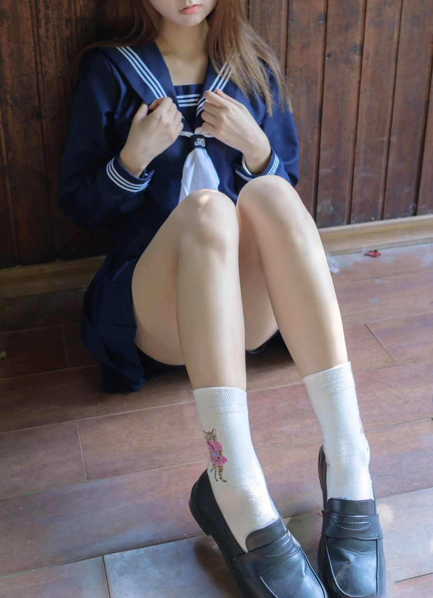 穿着蓝色裙子和白色袜子的女孩坐在一个步骤上。