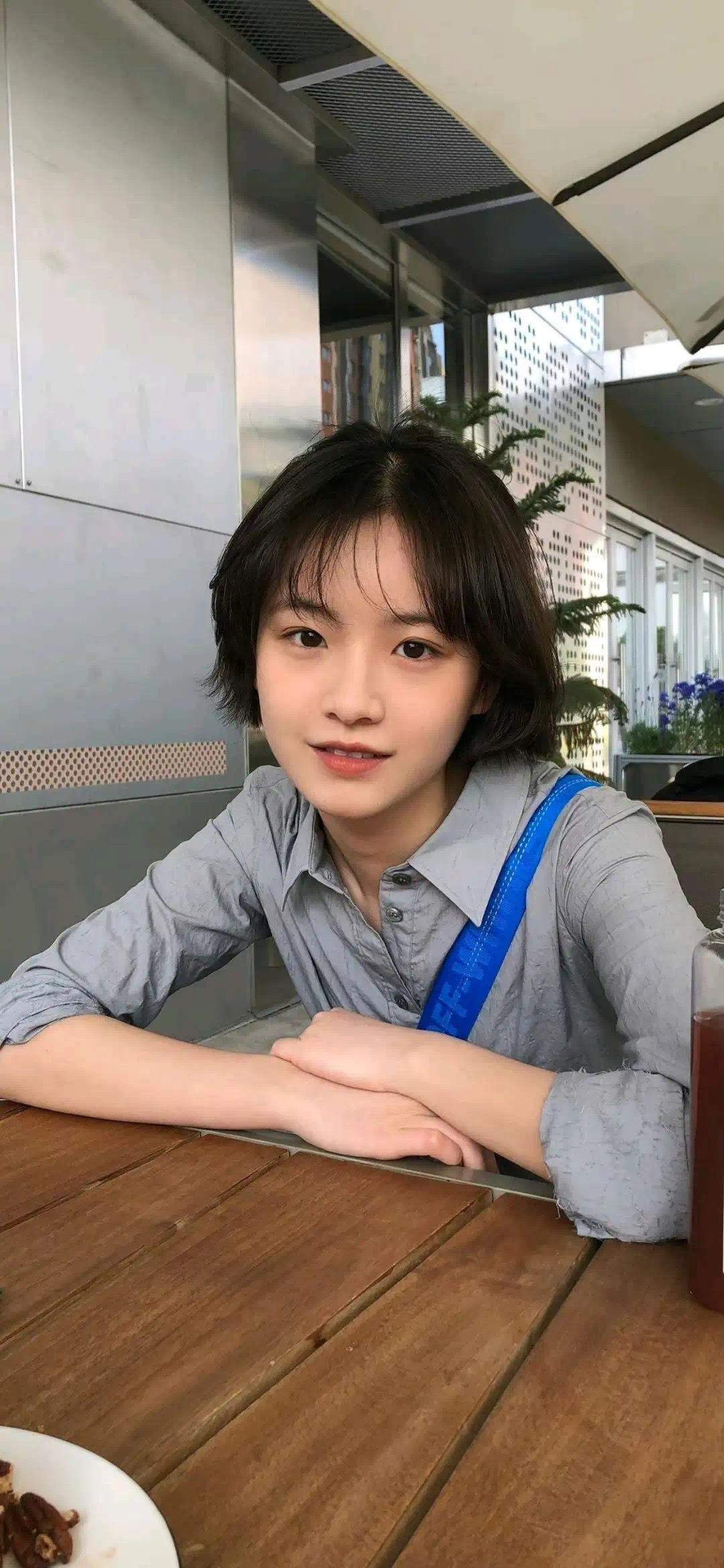 短发的女人和一个蓝色的袋子坐在桌子上。