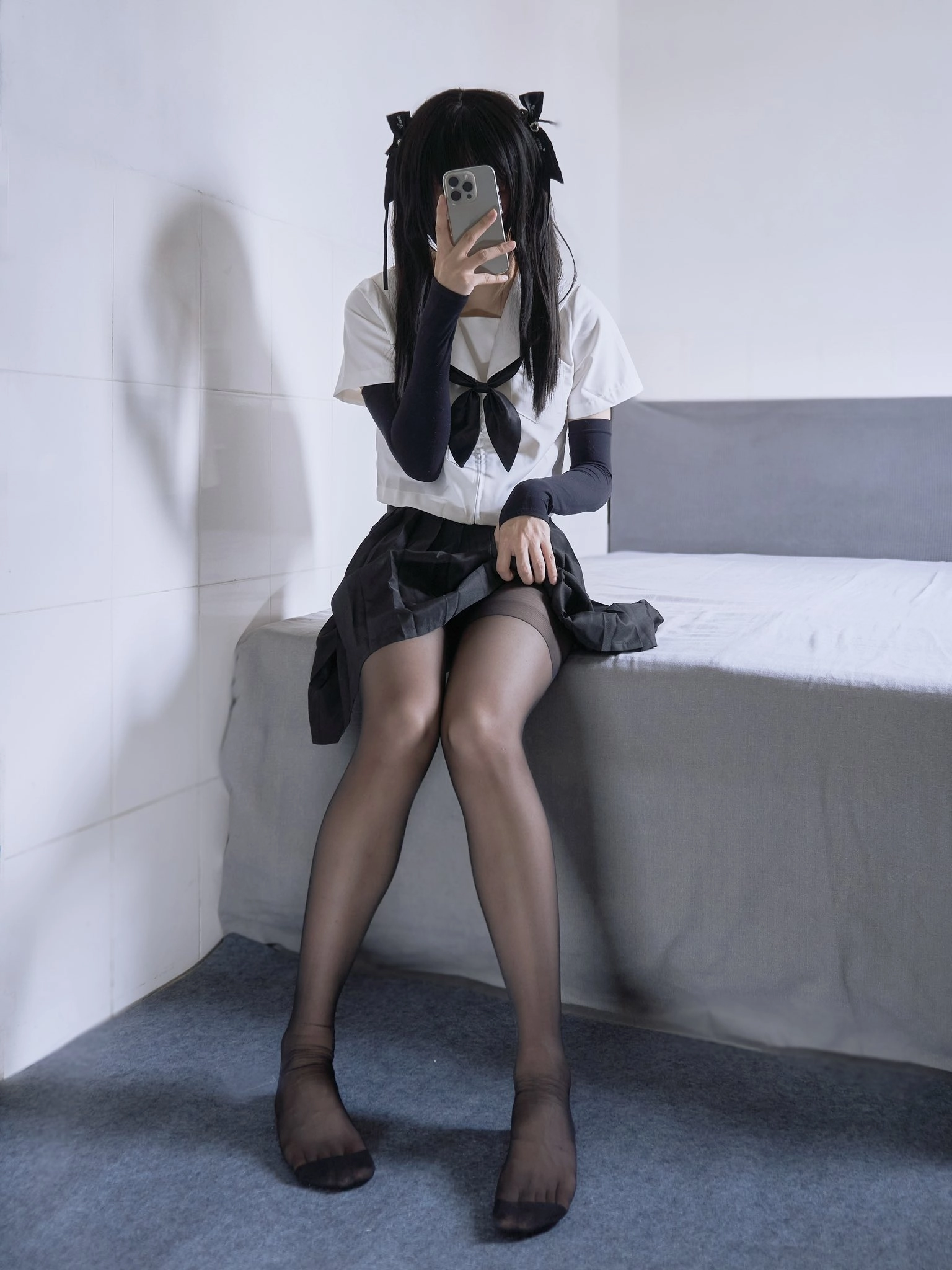 穿着黑色裙子和白色衬衫的女人坐在床上。