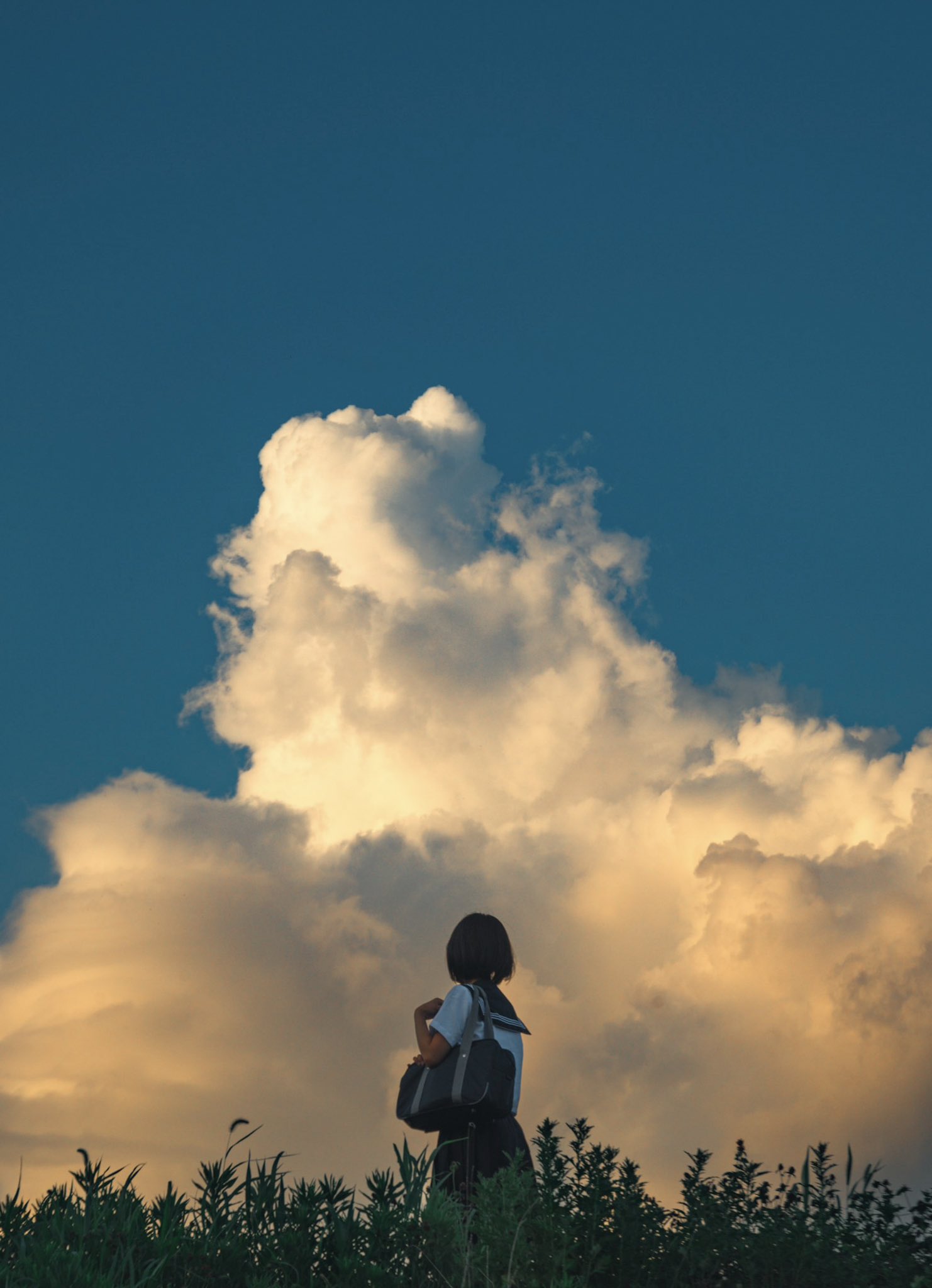 女人站在一座山上,仰望云层。