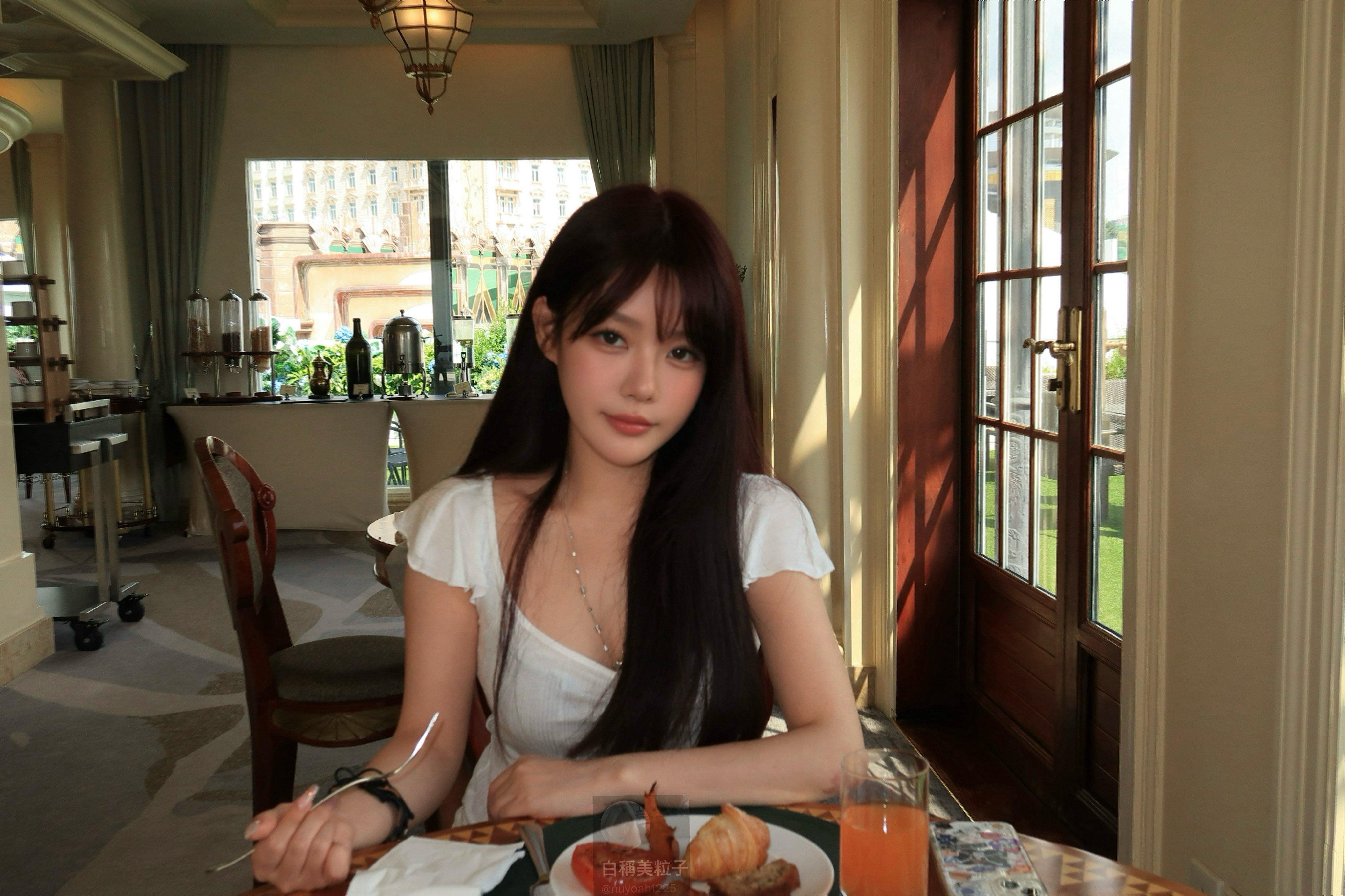 长头发和白衬衫的女人坐在一张带食物的桌子上。