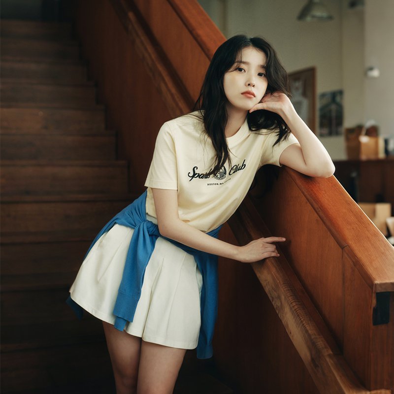 女人穿着一件黄色衬衫,上面有体育俱乐部标志。