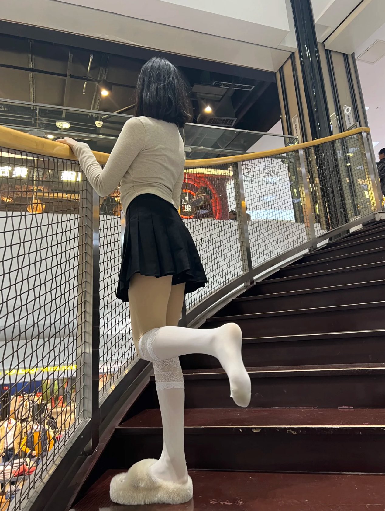 一位穿着白色袜子和黑色裙子的女人站在楼梯上。