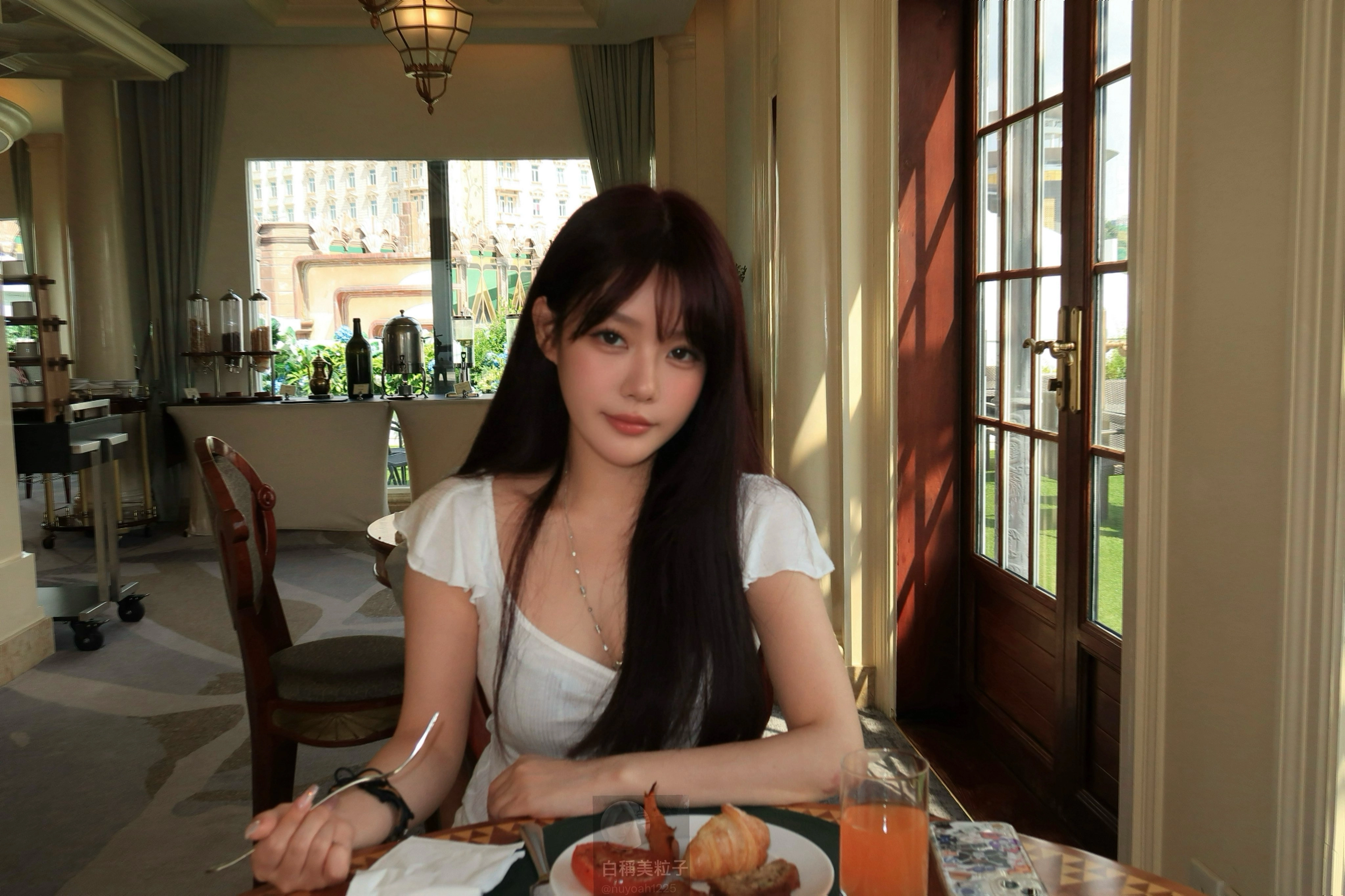 长头发和白衬衫的女人坐在一张带食物的桌子上。