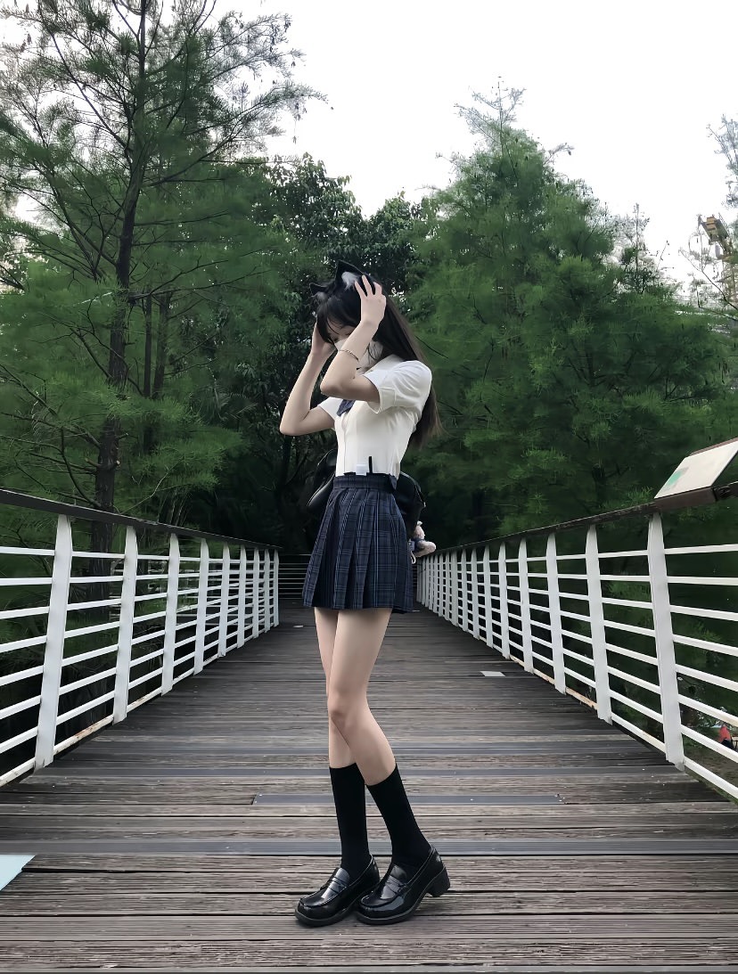 一位戴着猫帽和裙子的女人站在桥上。