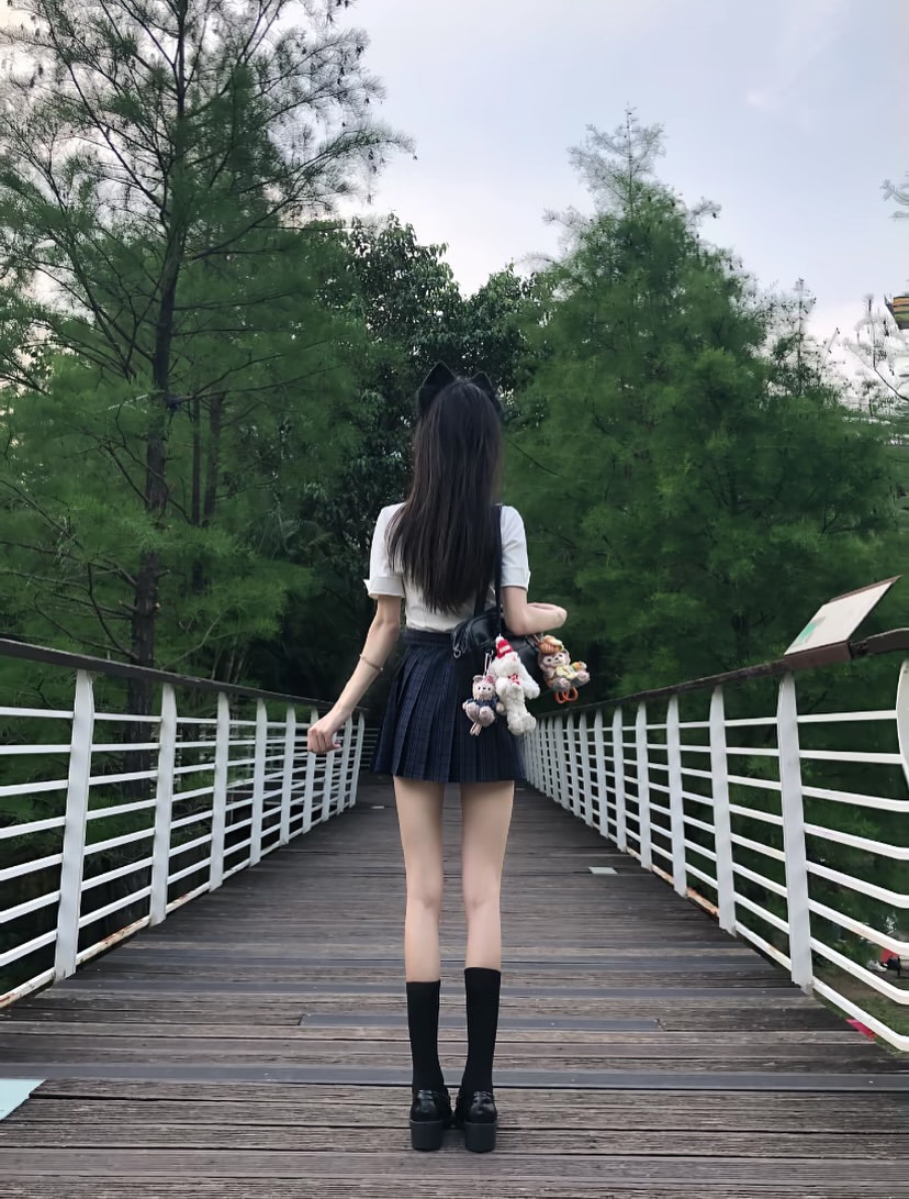 一位戴着猫帽和裙子的女人站在桥上。