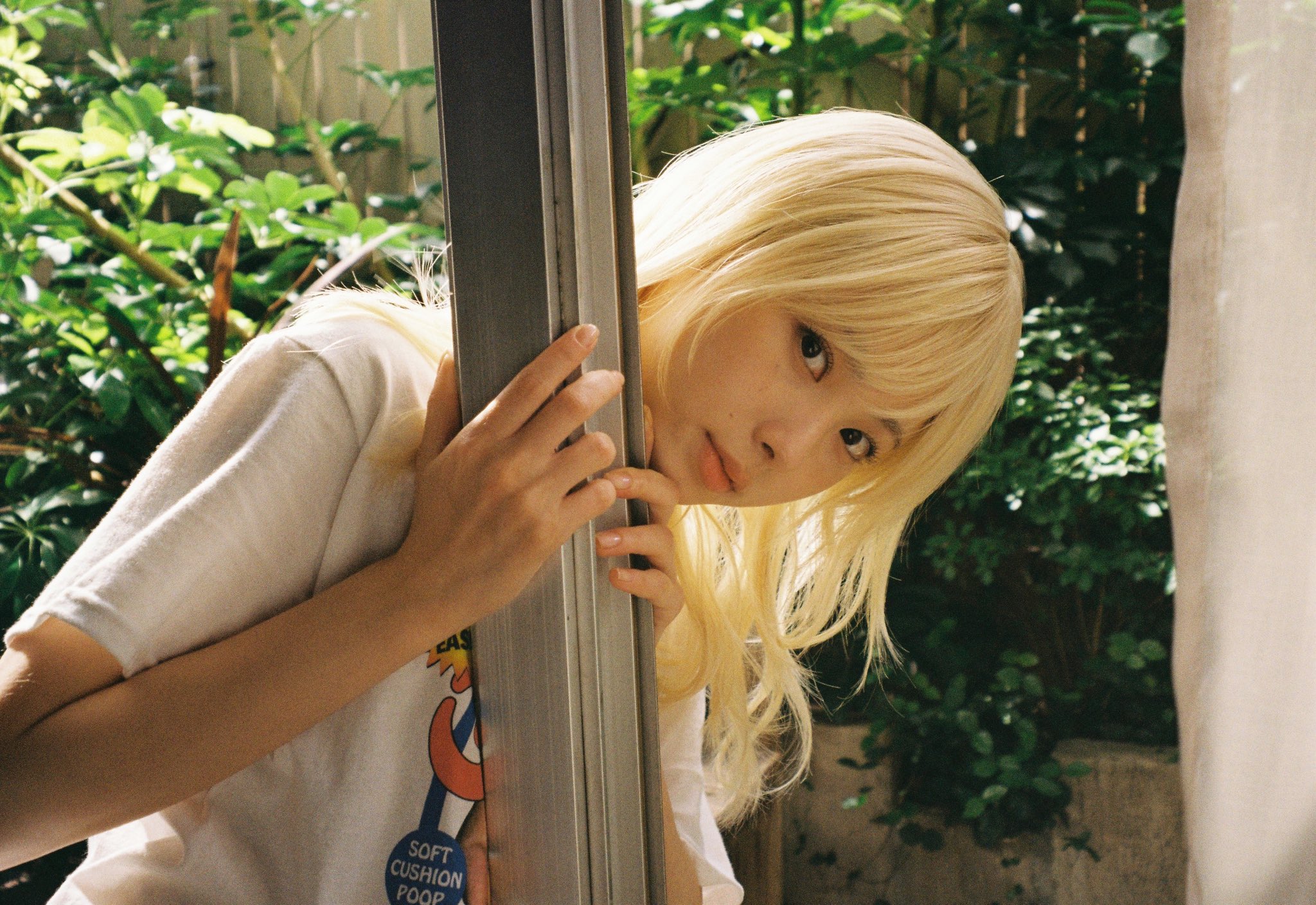 金发的女人和一件白色的衬衫倾斜在一个极点上。