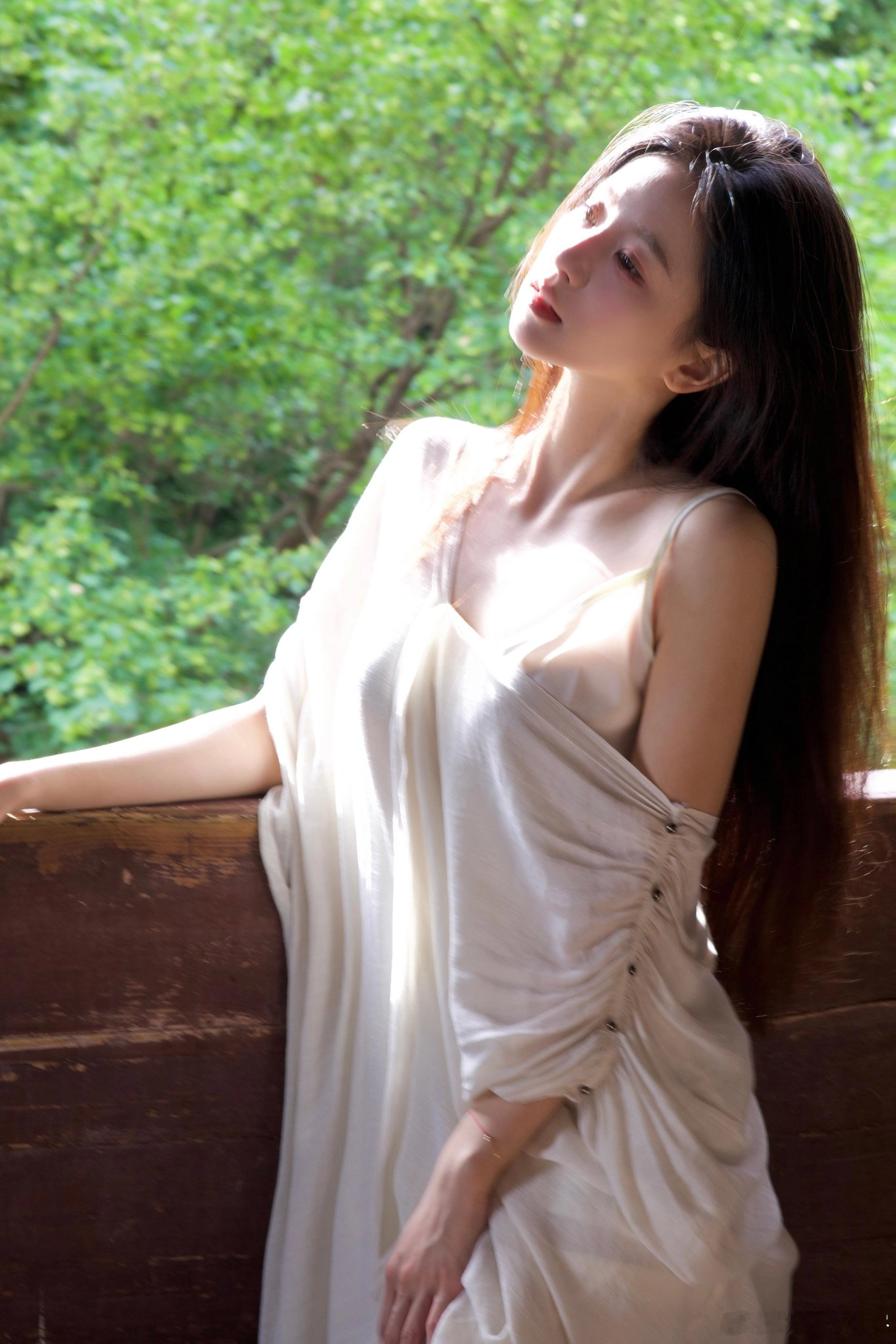 一位穿着白色衣服的女人坐在木墙上。