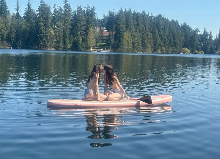 两个女人在水中的粉红色的架子上接吻。