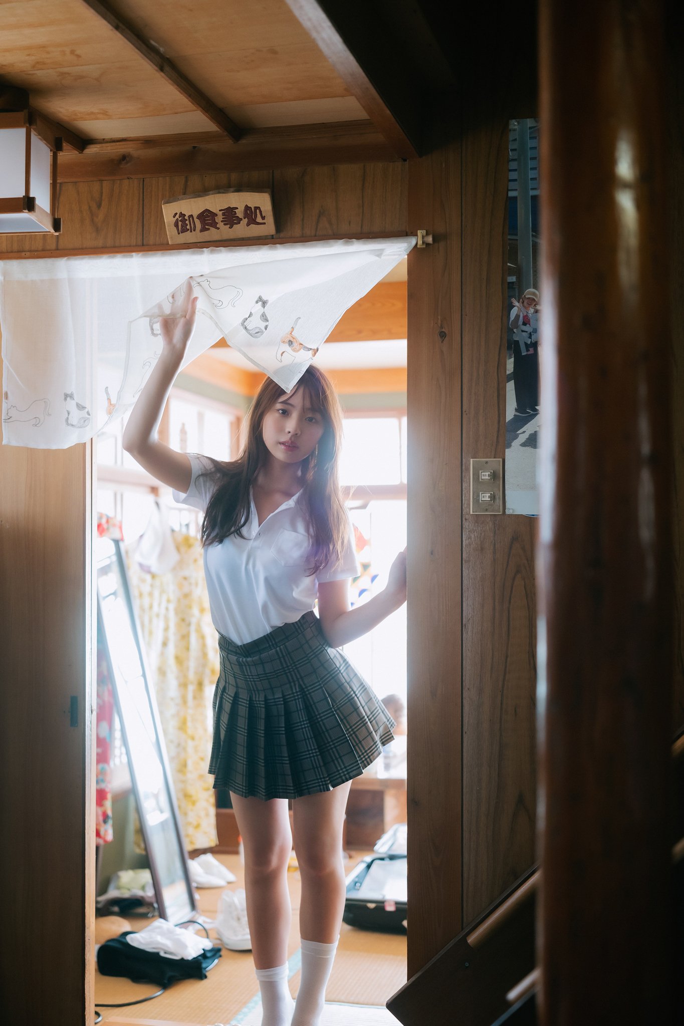 穿着白色衬衫和一件白色的裙子的女人站在门前。