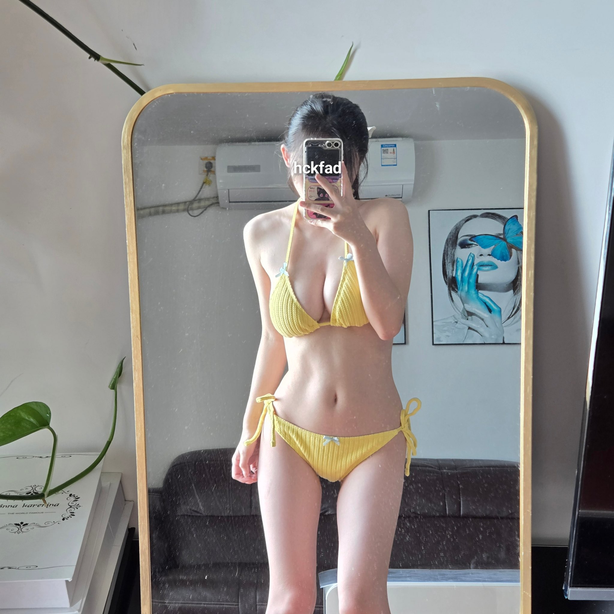 穿着黄色比基尼的女人在镜子前拍个自拍。