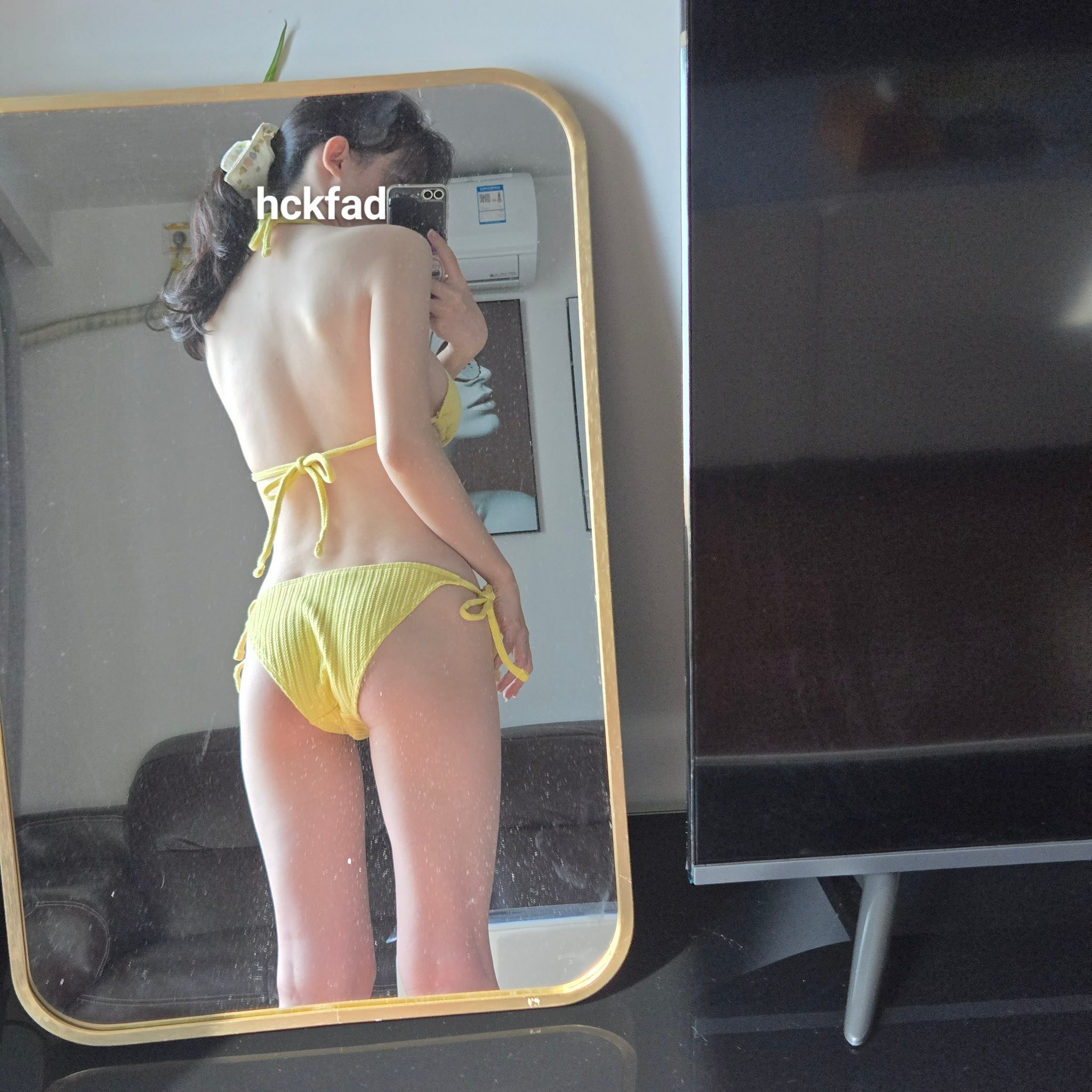 穿着黄色比基尼的女人在镜子前拍个自拍。