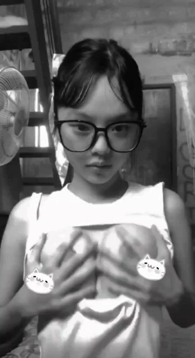 一位戴着眼镜和一件白色衬衫的女人握住她的乳房。