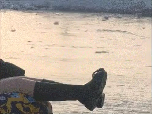 穿黑鞋和黑袜子的人坐在海滩上。