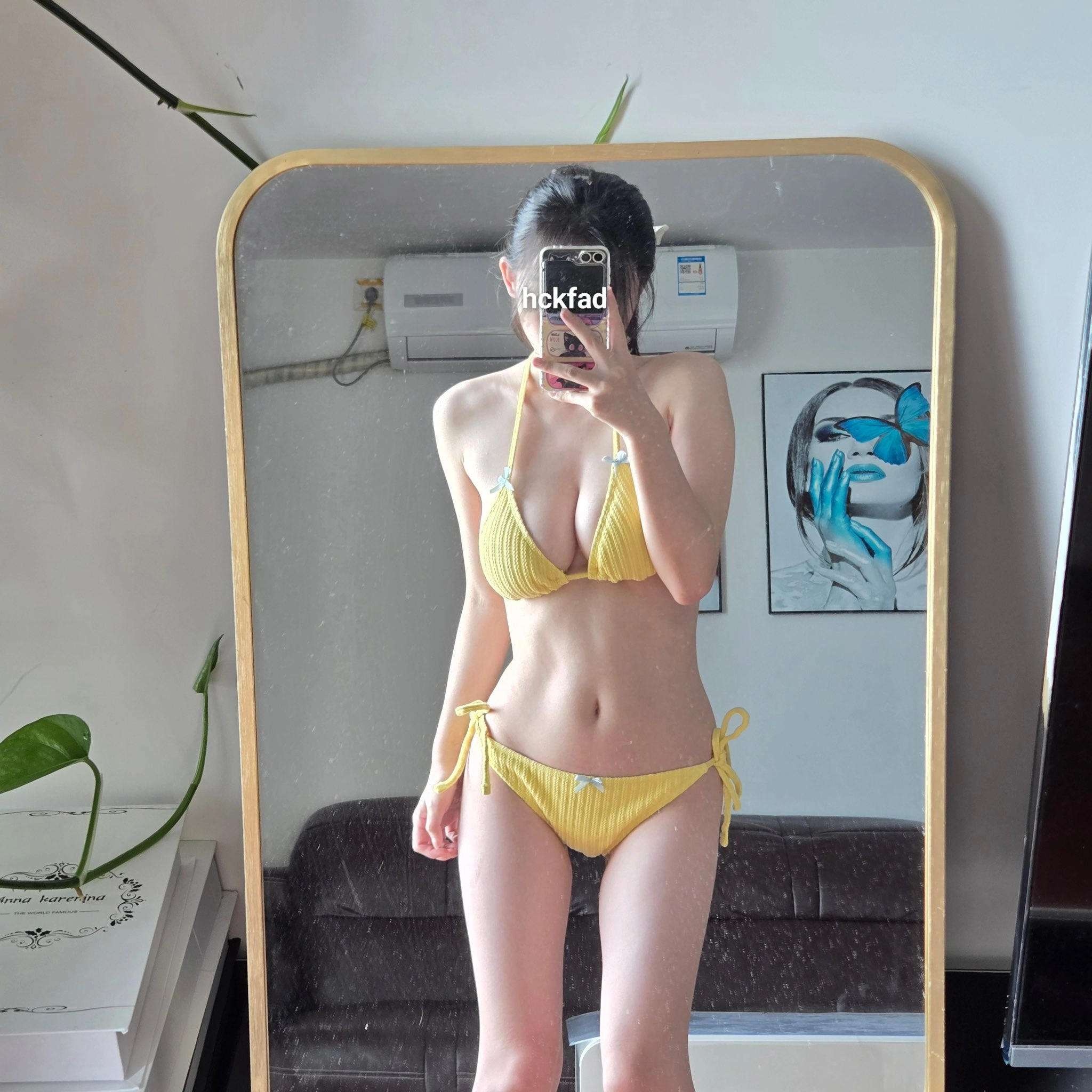 穿着黄色比基尼的女人在镜子前拍个自拍。