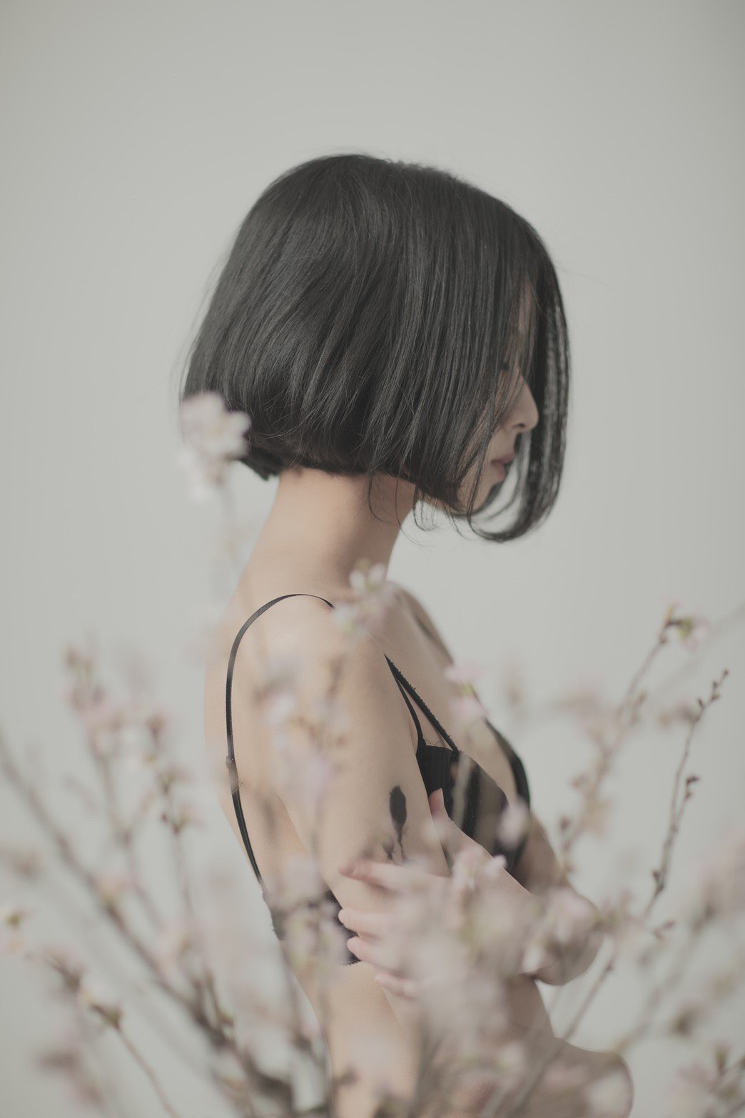 短发和黑头发的女人站在一棵有粉红色的花朵的树前。