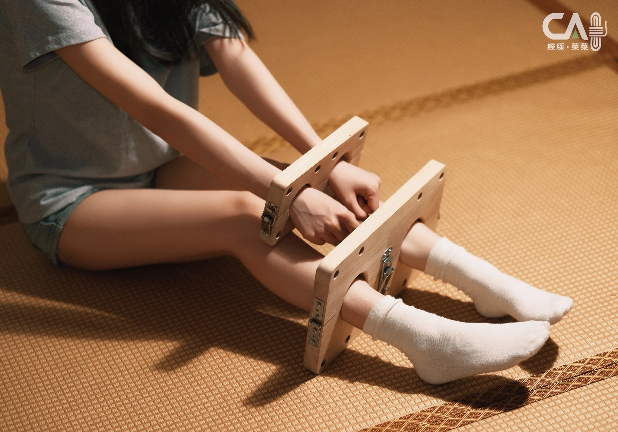 女人坐在地板上,手牵着木板。