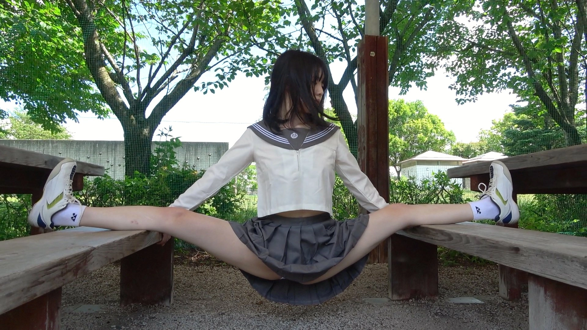 穿着学校制服的女人坐在一个凳子上,她的腿宽阔。