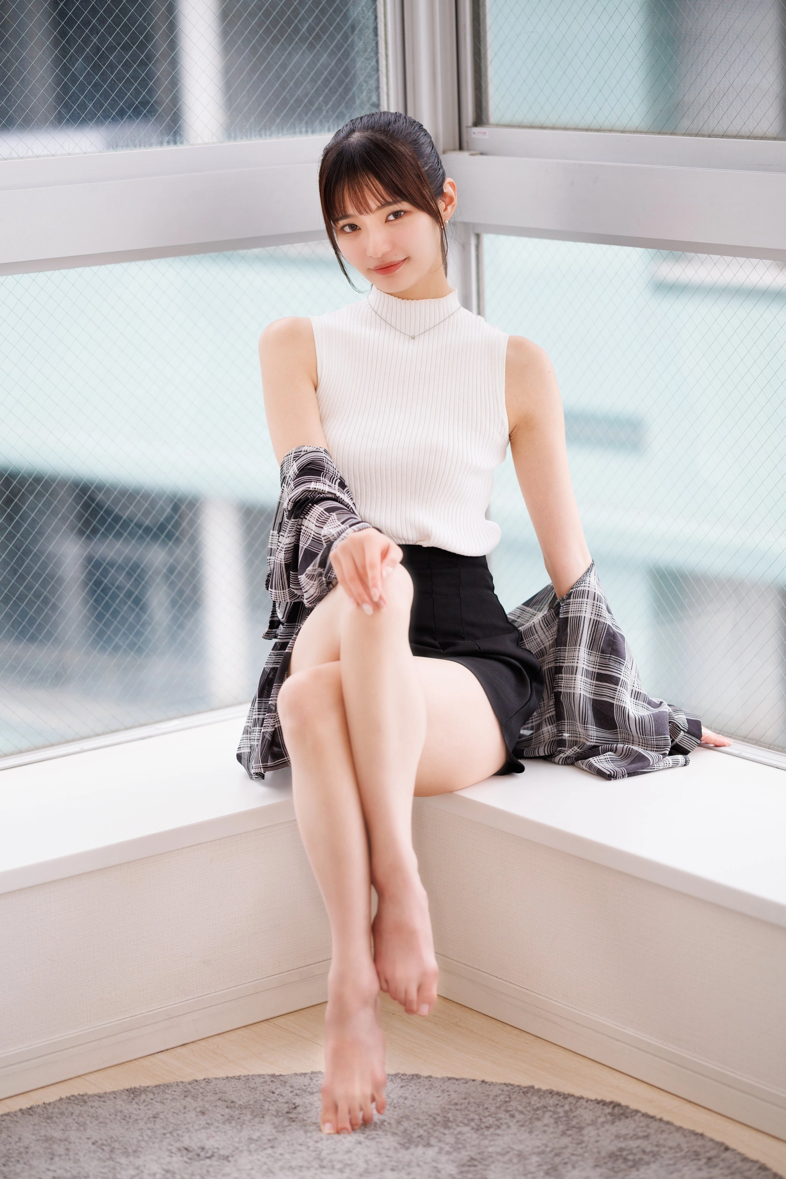 穿着白色衬衫和黑色短裤的女人坐在窗户上。