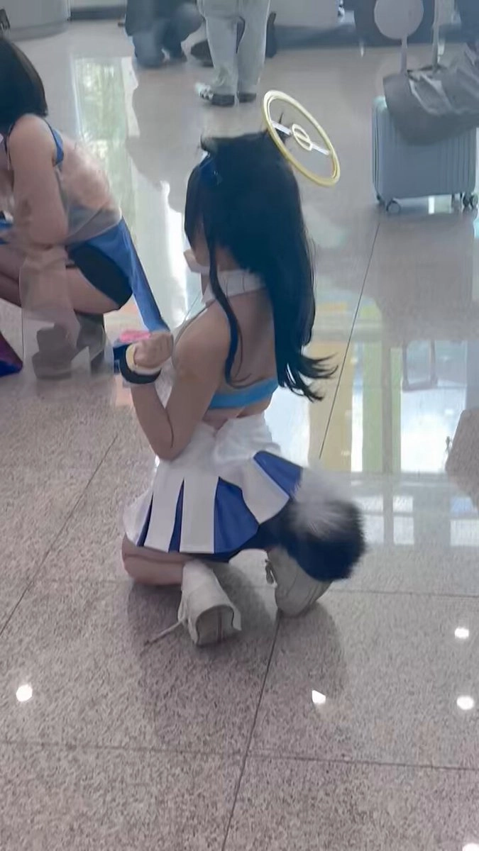 穿着蓝色和白色衣服的女孩跪在地板上。