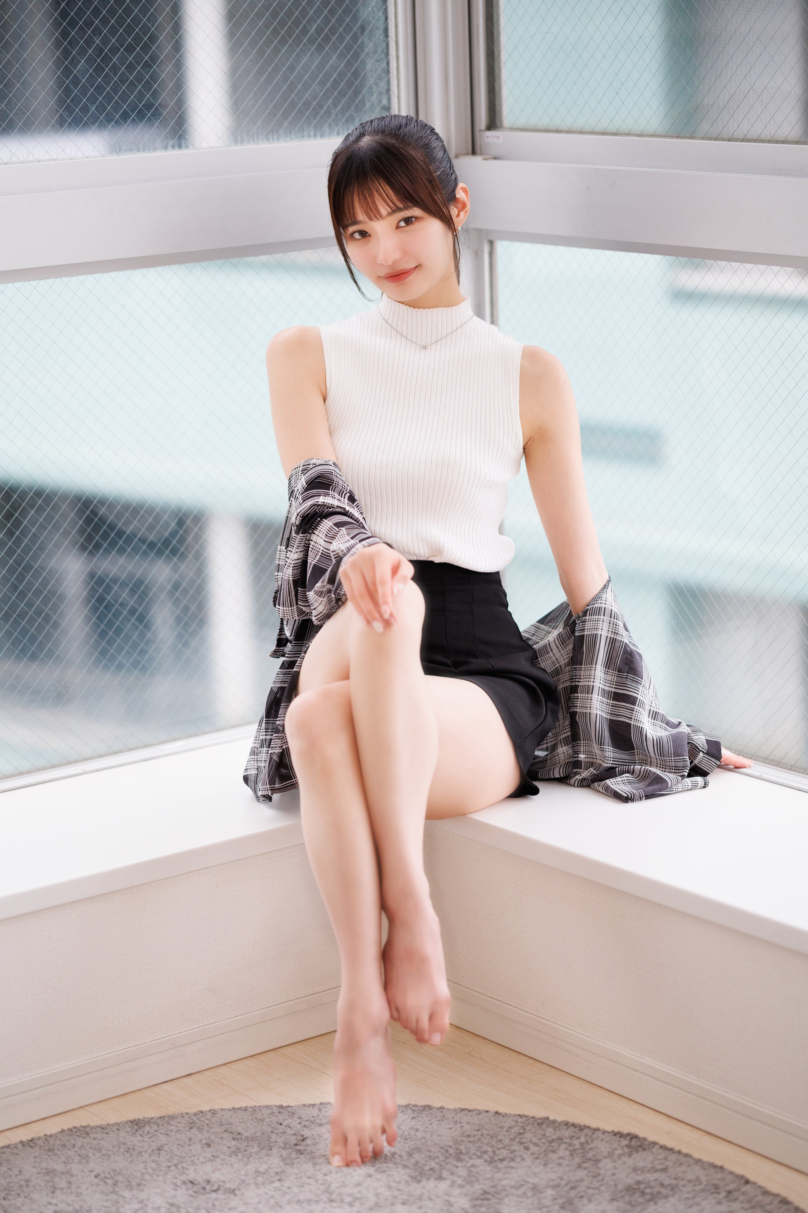 穿着白色衬衫和黑色短裤的女人坐在窗户上。