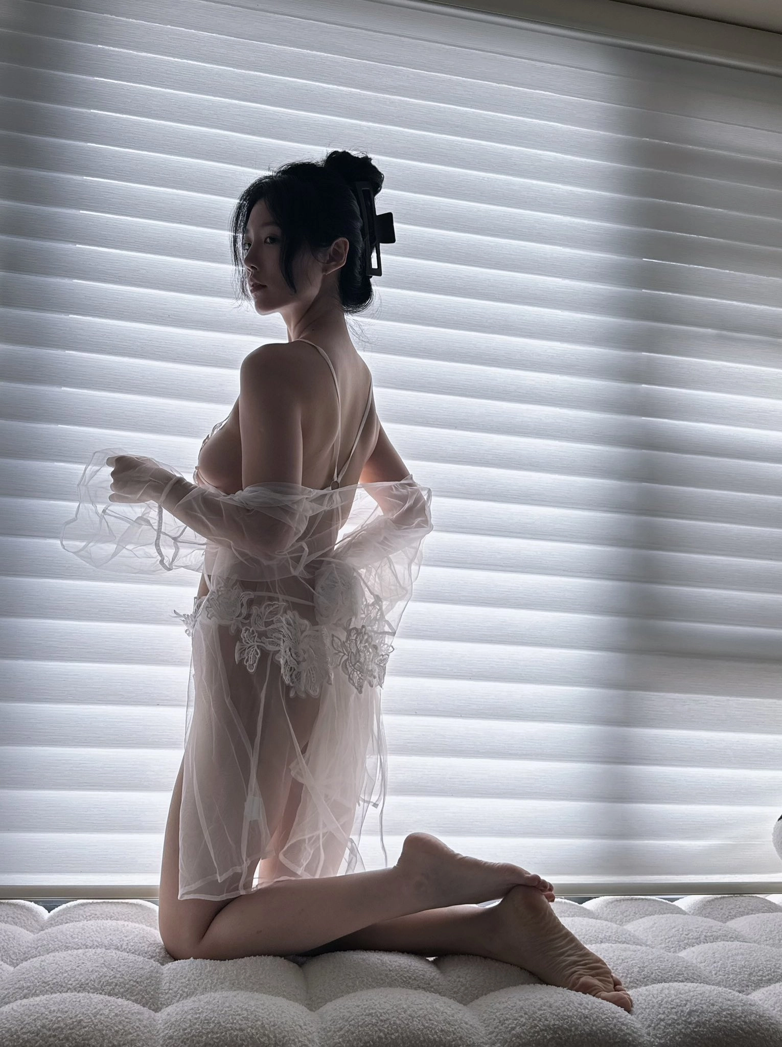 穿着白色衣服的女人站在窗前。