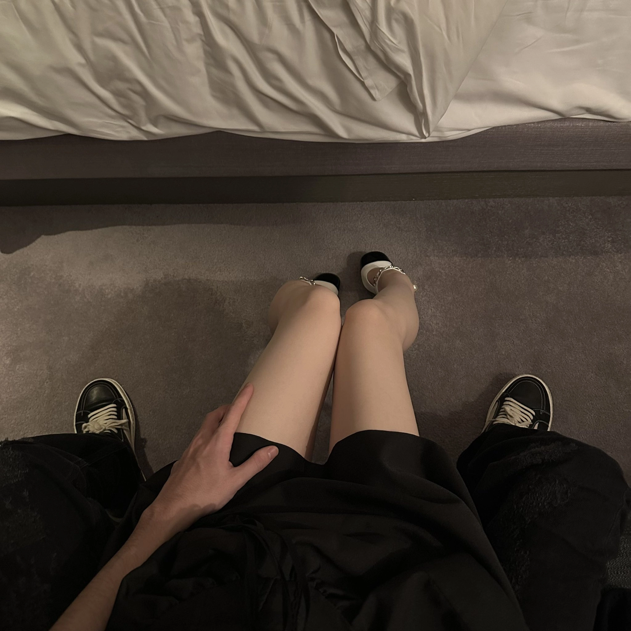 男人和一个女人坐在床上,一个女人穿着黑色的裙子和黑色的鞋子。