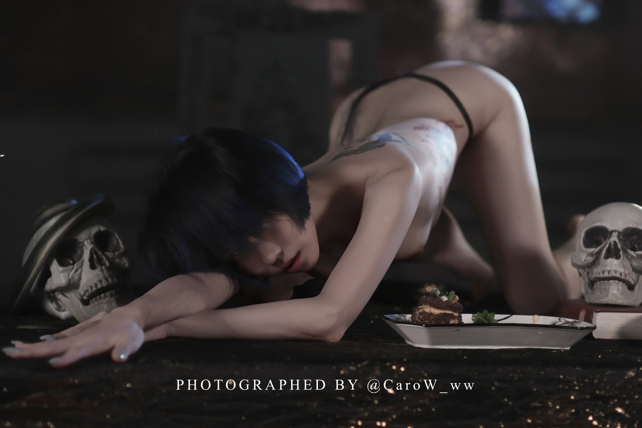 蓝头发和纹身手臂的女人躺在地板上。