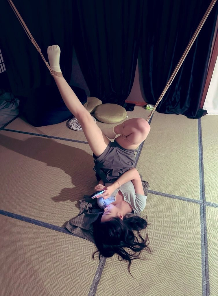 女人用手机躺在地板上。