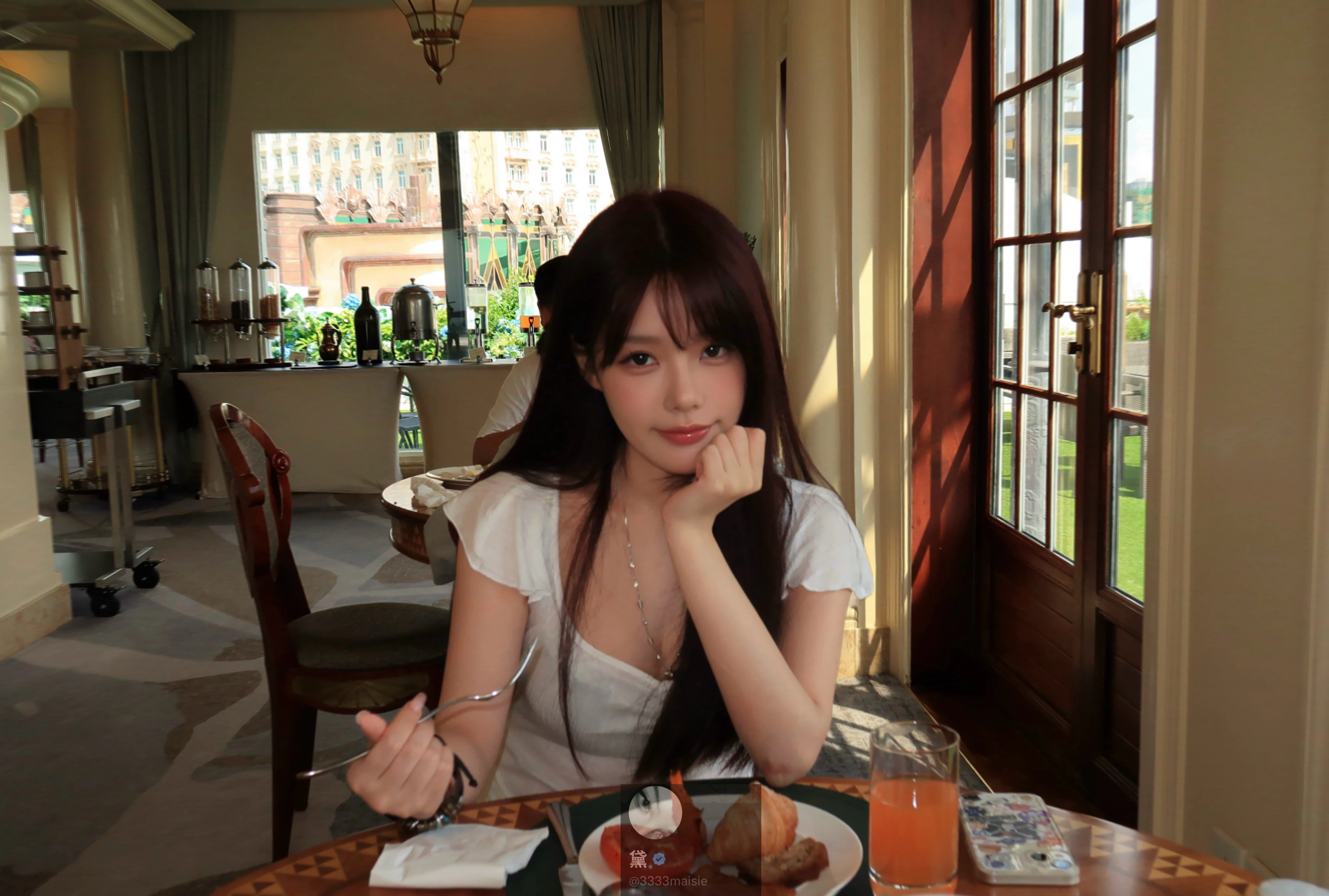 一位穿着白色衬衫的女人坐在桌子上,她面前有一盘食物。