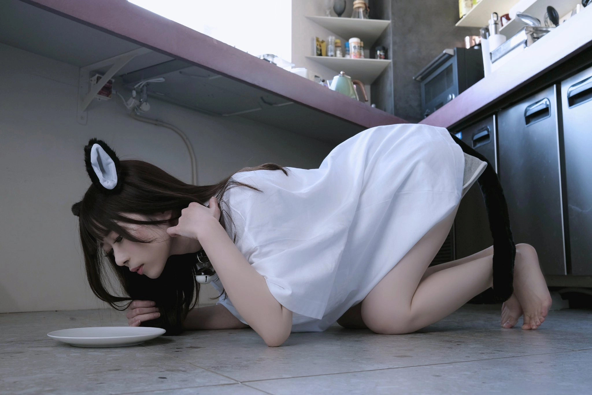 一位穿着白色衣服的女人跪下,吃了一盘食物。