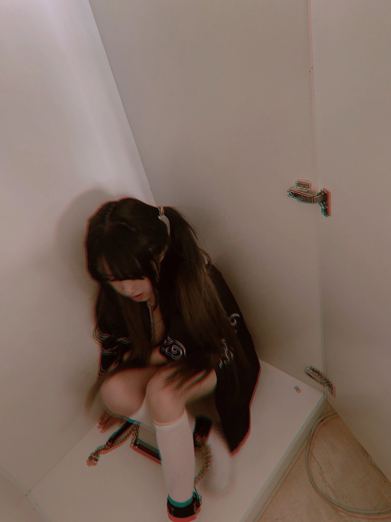 穿着黑色衬衫和白色袜子的女人坐在一个角落。