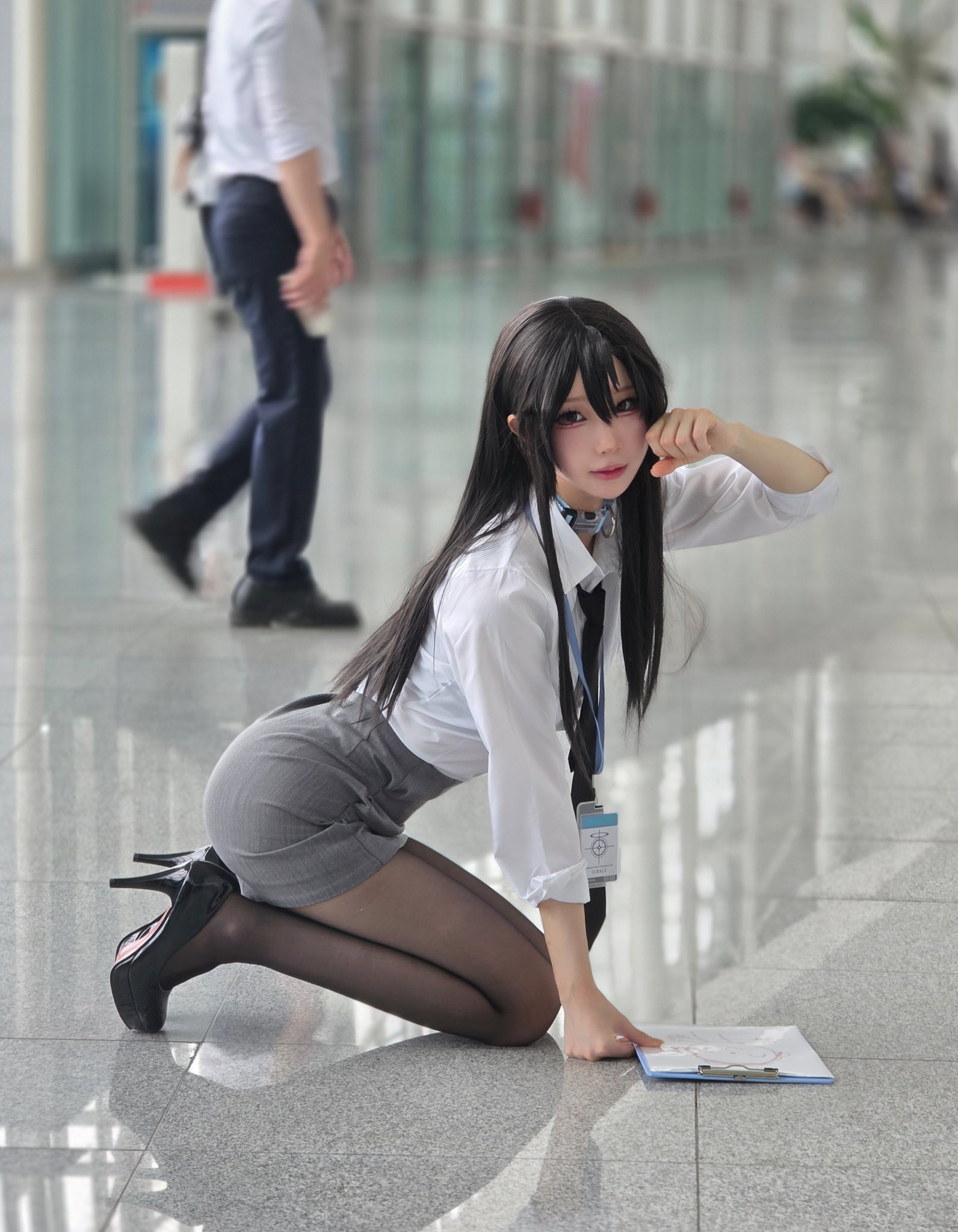 穿着白色衬衫和黑色裙子的女人跪在地板上。