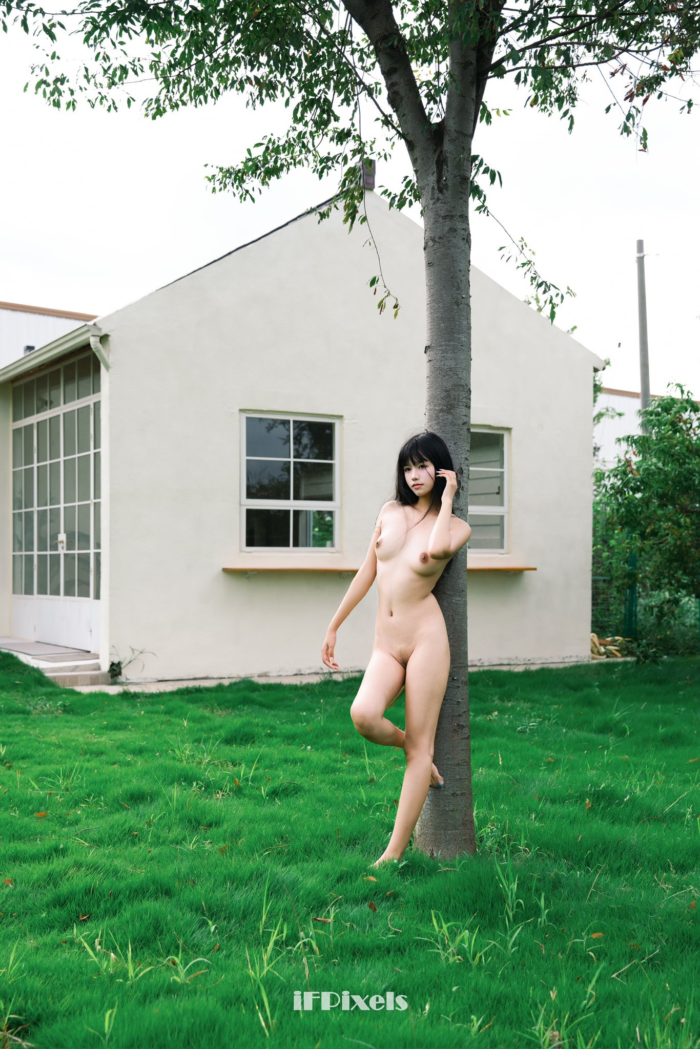 裸体的女人站在一棵树前。