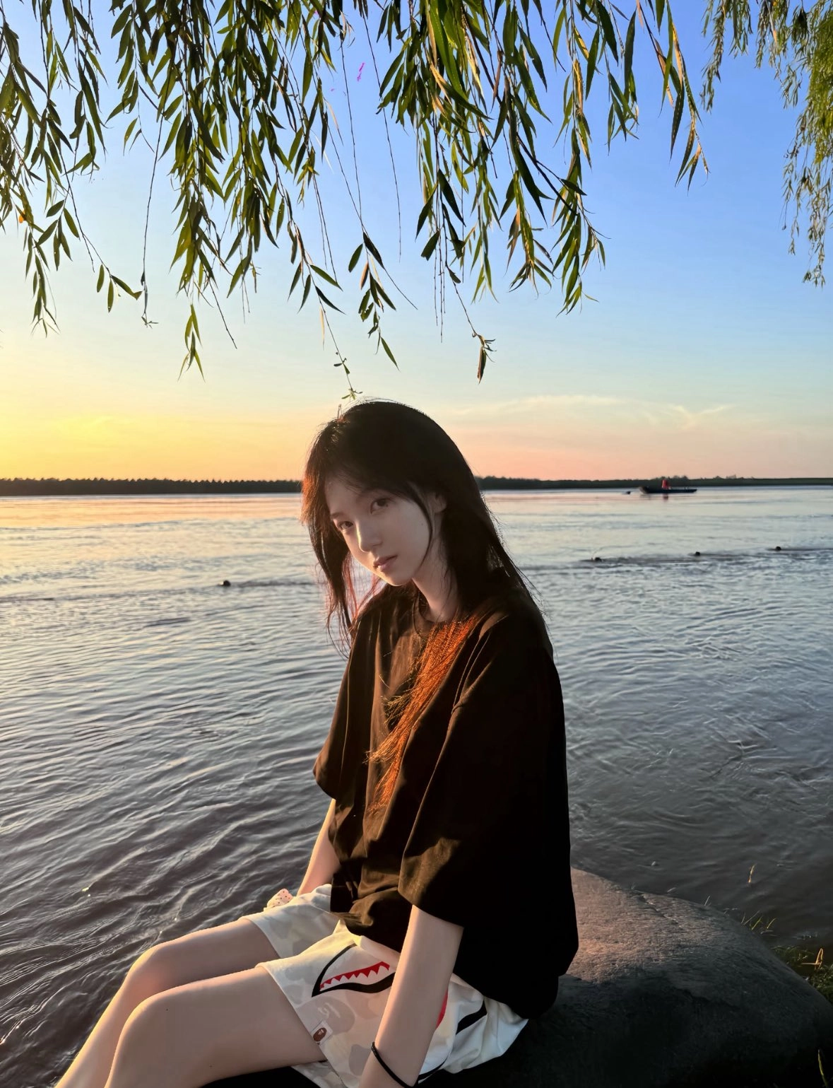 女人坐在水边的岩石上。