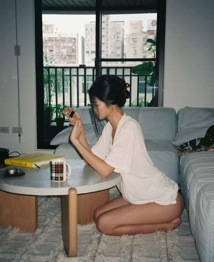 穿白衬衫的女人坐在桌子前的地板上。